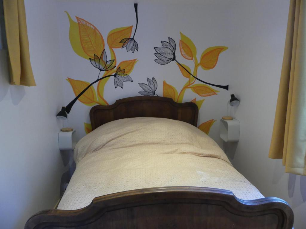 1 dormitorio con 1 cama con un mural de flores en la pared en Maison de village au calme axe Annecy - Genève en Villy-le-Pelloux