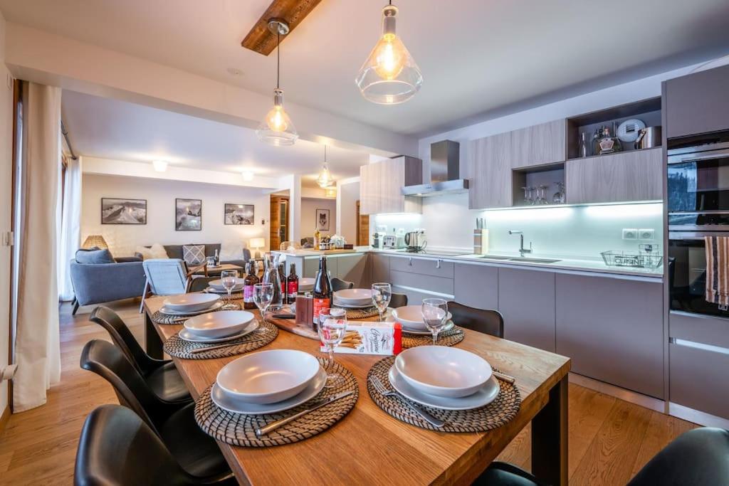 kuchnia i jadalnia z drewnianym stołem i krzesłami w obiekcie Appartement Abela 10 Pers Domaine de Serre Chevalier w mieście Saint-Chaffrey
