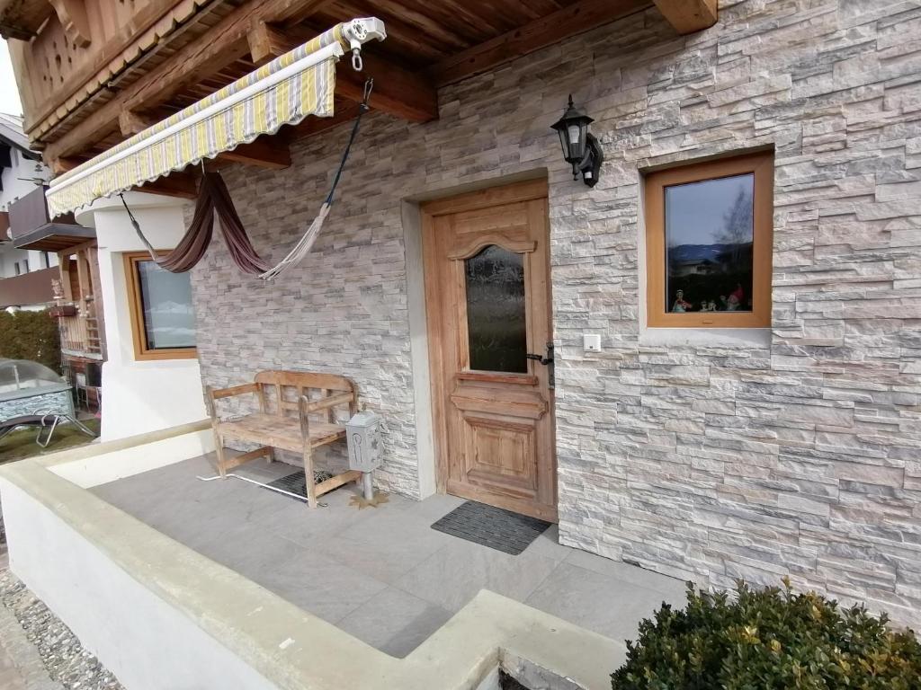 Casa de piedra con puerta de madera y banco en Ferienwohnung Konrad, en Kirchdorf in Tirol
