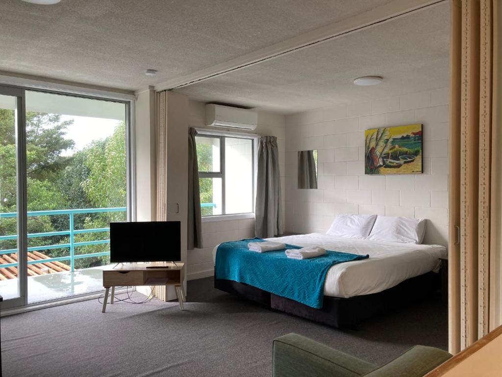 a bedroom with a bed and a television and a balcony at City Towers Apartments in Auckland