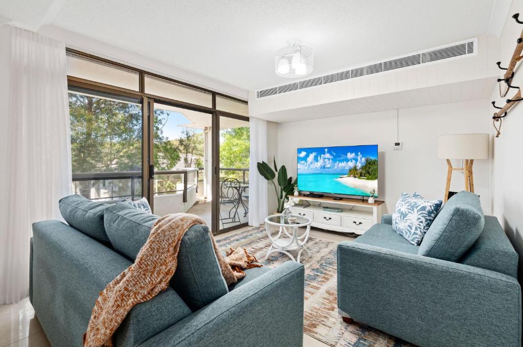 a living room with two blue couches and a tv at The Commodore in Nelson Bay