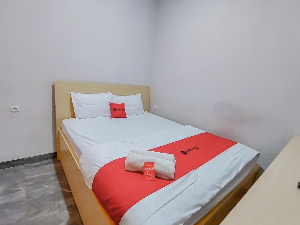 Reddoorz at Cempaka Guesthouse Tarakan في Sibengkok: غرفة نوم صغيرة مع سرير بملاءات حمراء وبيضاء