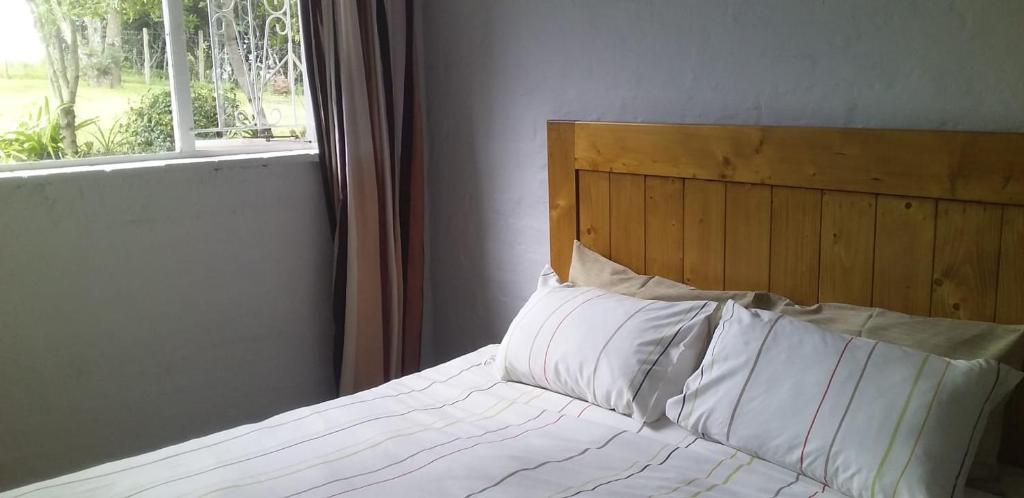sypialnia z łóżkiem z białymi poduszkami i oknem w obiekcie Bergview Chalet, Cathkin w mieście Bergview