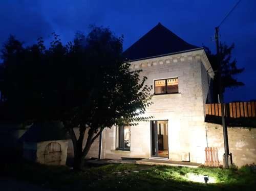 Una casa blanca con un árbol delante. en Gîte Saumur Le Pigeonnier, Calme et Cosy, en Épieds