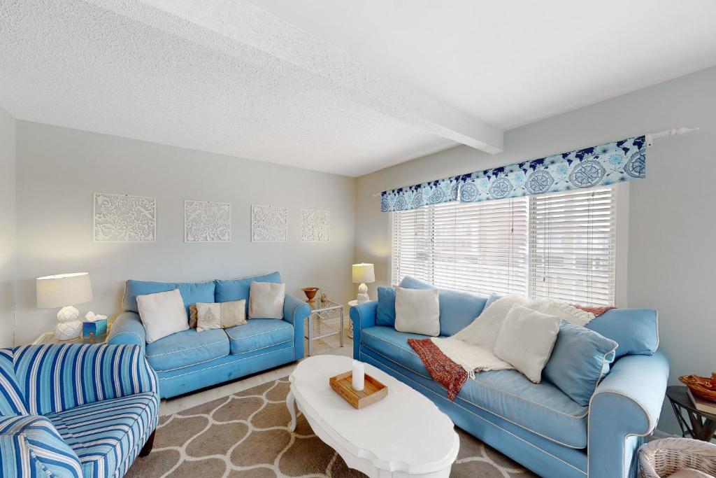 uma sala de estar com sofás azuis e uma janela em Dewey Villas --- 24 Dickinson Ave, Unit #8B em Dewey Beach