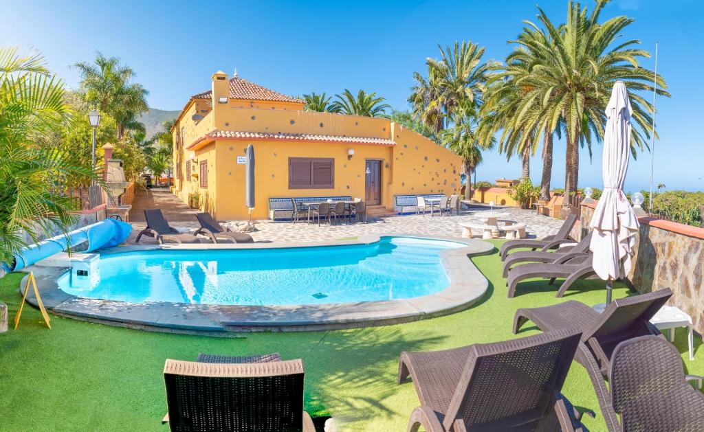 una piscina con sillas y una casa en el fondo en Pradera de Melo Heated Pool on request-Wifi-BBQ en Los Realejos