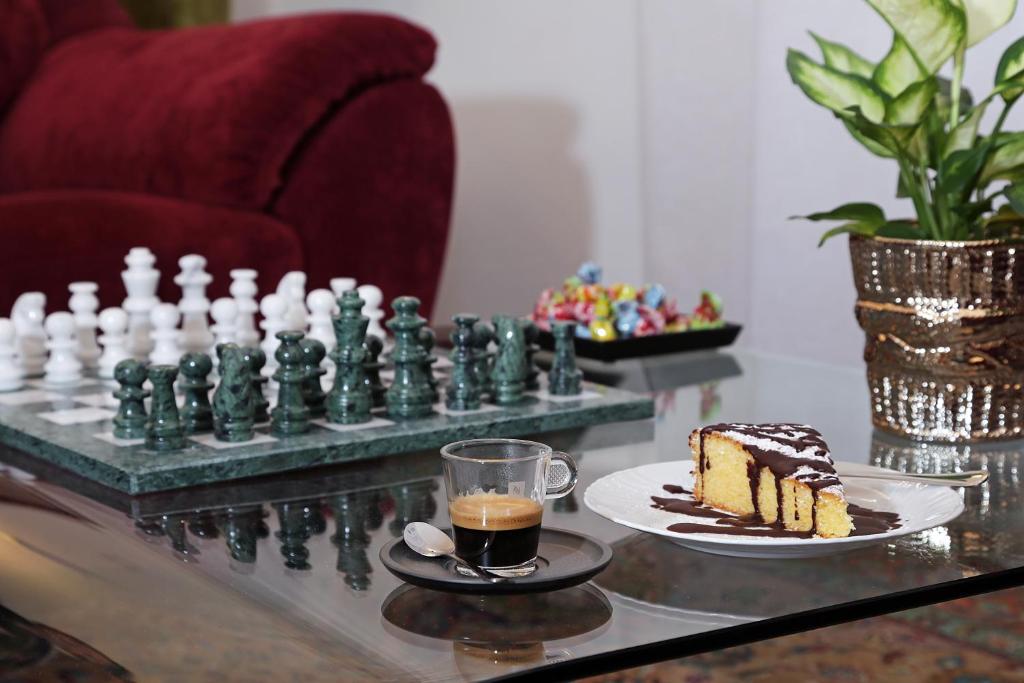 un tablero de ajedrez y una rebanada de pastel en una mesa en Houspitality Caesar Bed & Breakfast, en Roma
