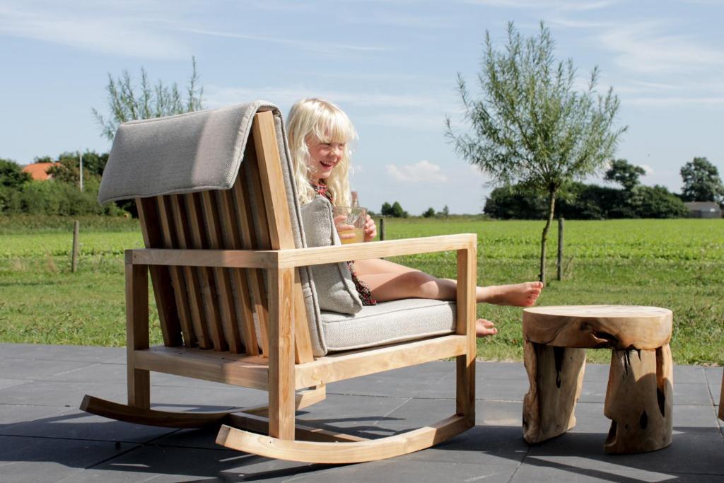 une femme assise dans une chaise à bascule à côté d'un tabouret dans l'établissement Slufterhoeve, à De Cocksdorp