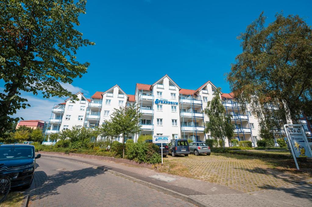 ein großes weißes Gebäude mit Autos auf einem Parkplatz in der Unterkunft Strandruh Apartments in Binz