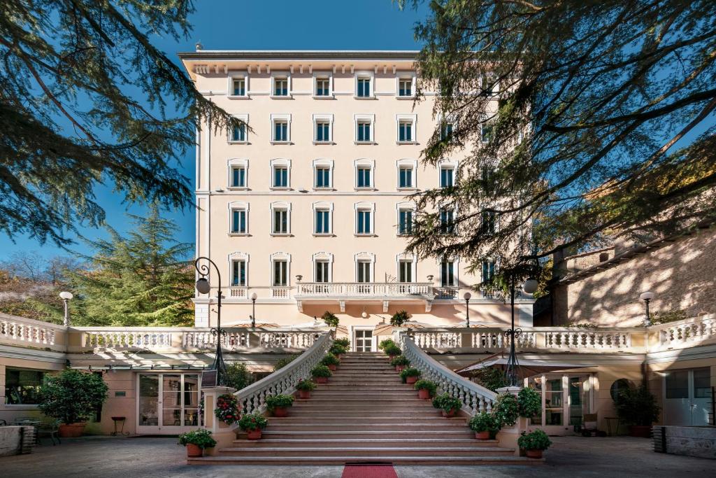 Un escalier mène à un grand bâtiment blanc. dans l'établissement Hotel Helvetia Thermal Spa, à Porretta Terme