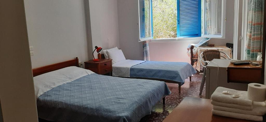 a bedroom with two beds and a desk and window at Myrto in Tyros