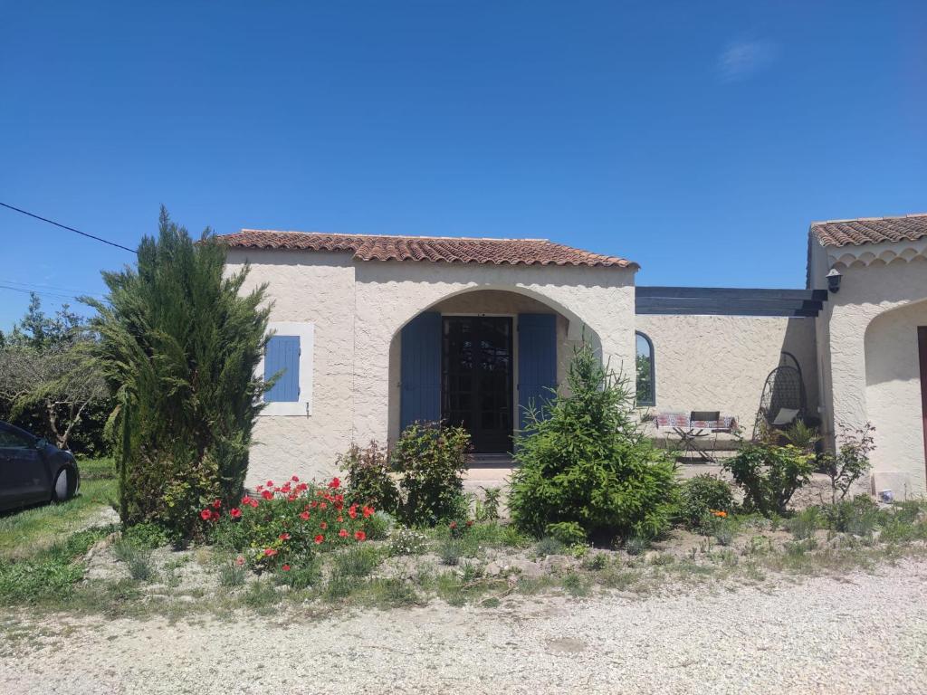 a house with a porch and flowers in front of it at Studio en pleine campagne in Le Thor