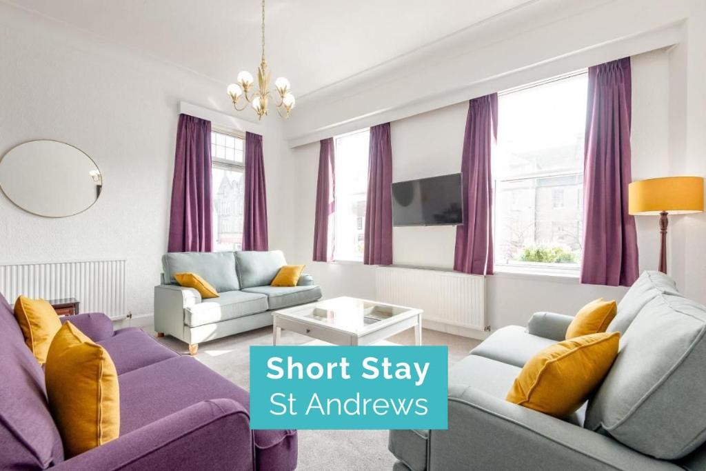a living room with purple furniture and purple curtains at The Cross Keys Market Street Apartment - Sleeps 6 in St Andrews