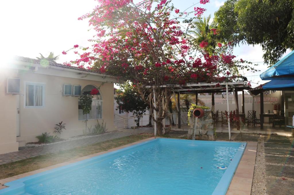 - une piscine en face d'une maison ornée de fleurs roses dans l'établissement Pousada Ponta Negra, à Natal