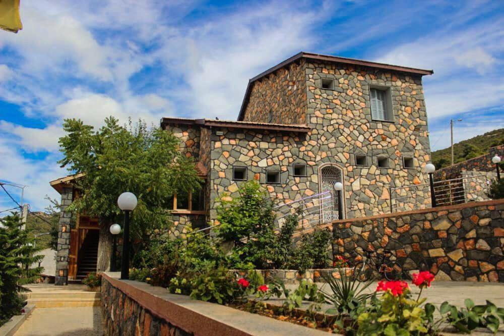 una casa de piedra con flores delante en Hôtel les truites, en Imouzzer Kandar