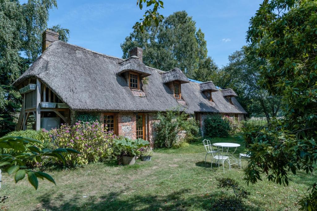 an old house with a thatched roof and a table at Cottage les forières in Saint-Honoré