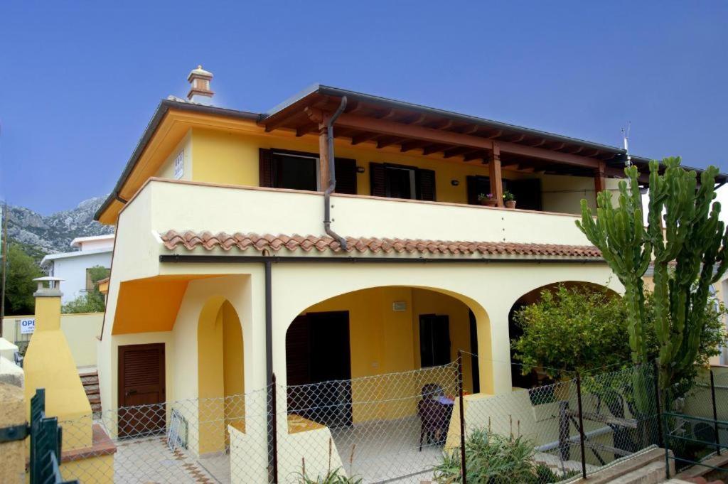 una casa amarilla con una valla delante de ella en Affittacamere Casa del Sole, en Cala Gonone