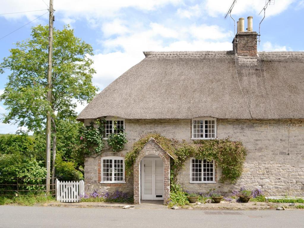 an old stone house with a thatched roof at The Old Post Office in Yellowham Wood