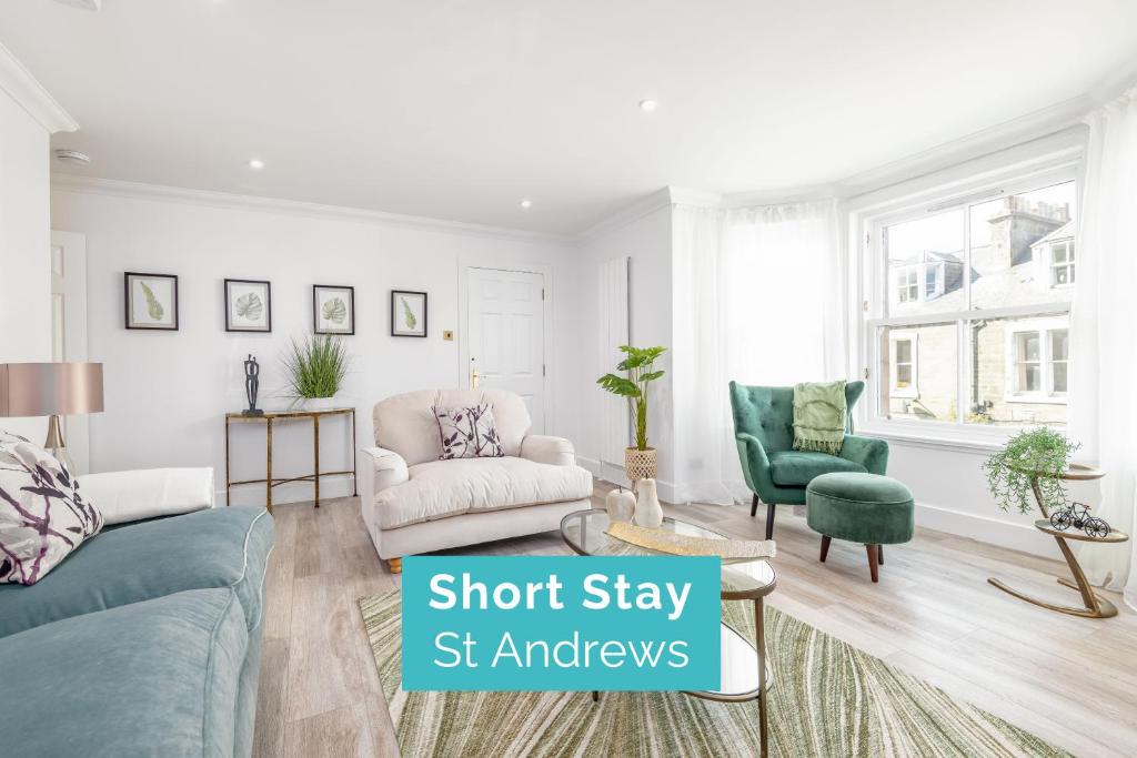 a living room with a blue couch and two chairs at Skye Sands - City Road Residence - Central St Andrews in St Andrews