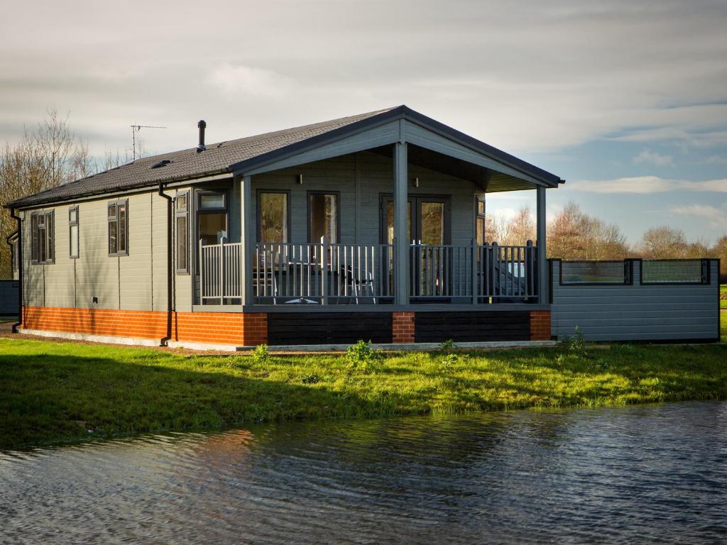 a house with a large porch next to a body of water at Beech - Ukc4530 in Darsham