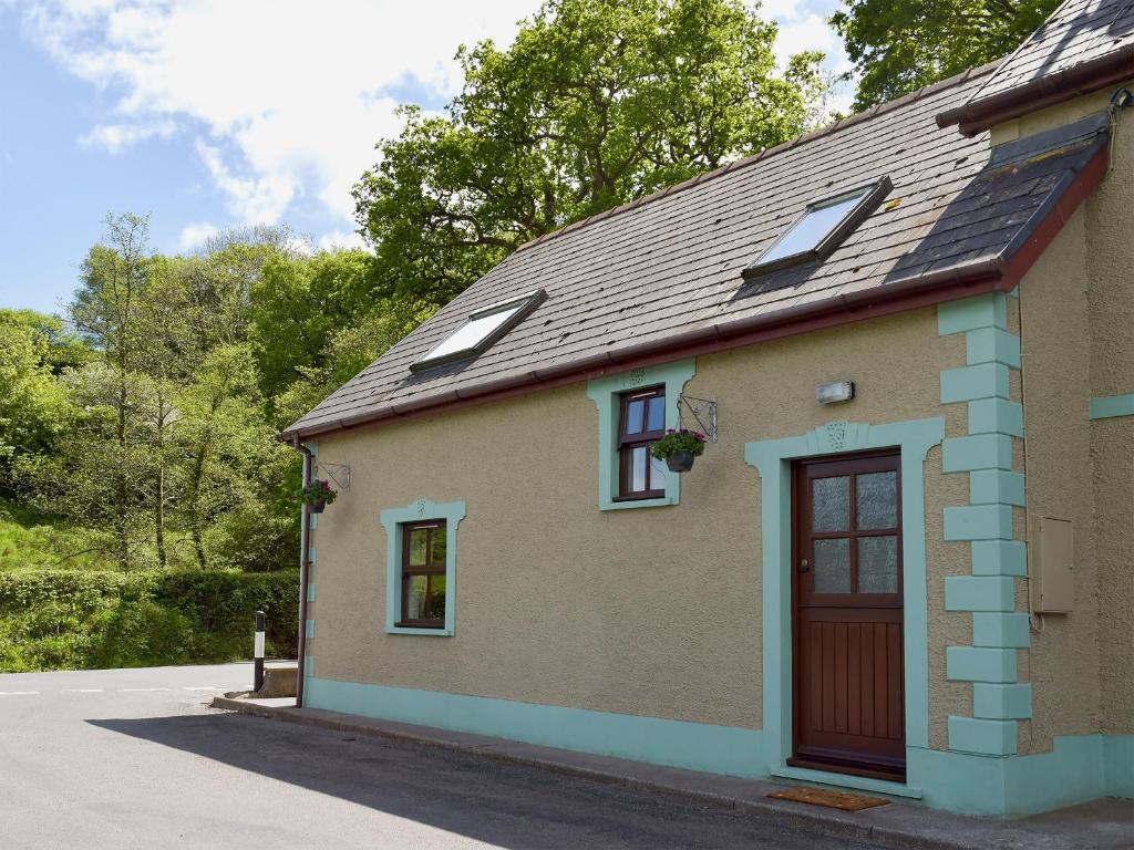 a small house with a red door and windows at Yr Efail Argoed in Llandowror