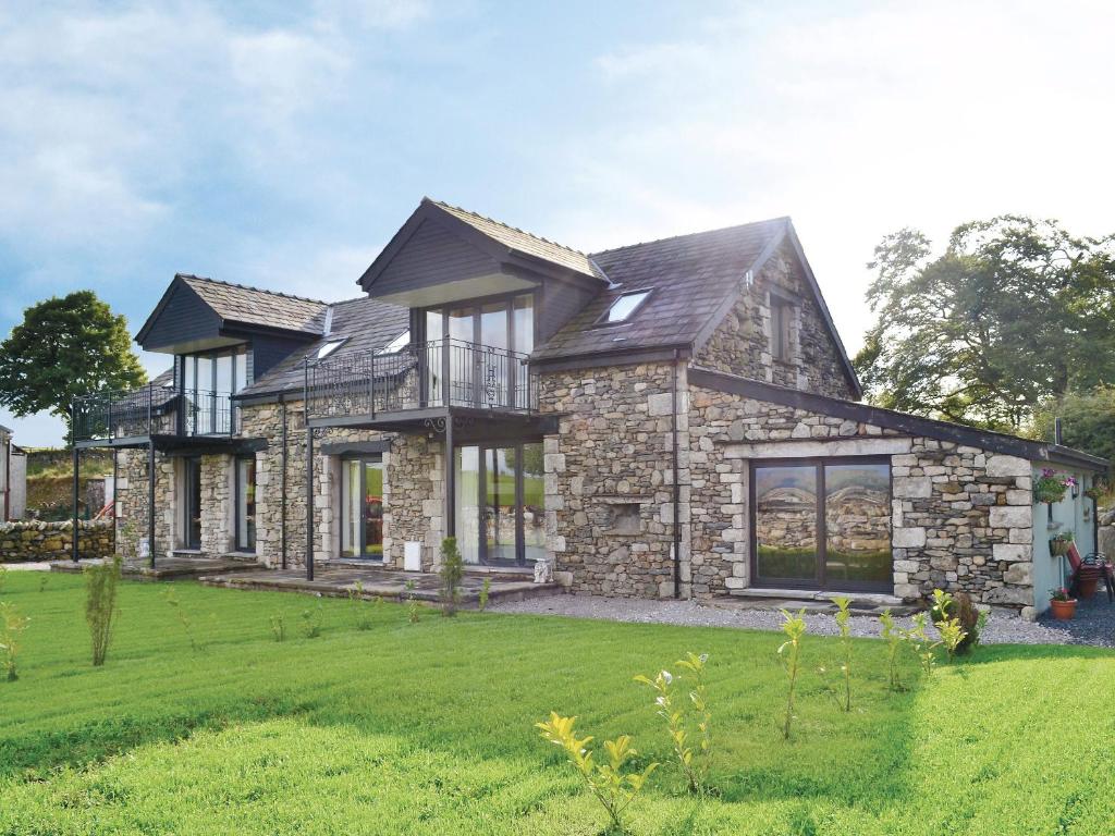 a large stone house with a green lawn at The Den in Grayrigg
