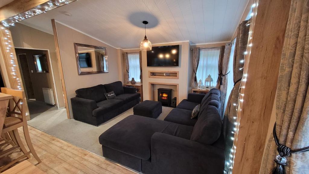 a living room with a couch and a fireplace at STUNNING, PEACEFUL LODGE on edge of New Forest and 800m from sea ENTERTAINMENT and LEISURE PASSES INCLUDED in Milford on Sea