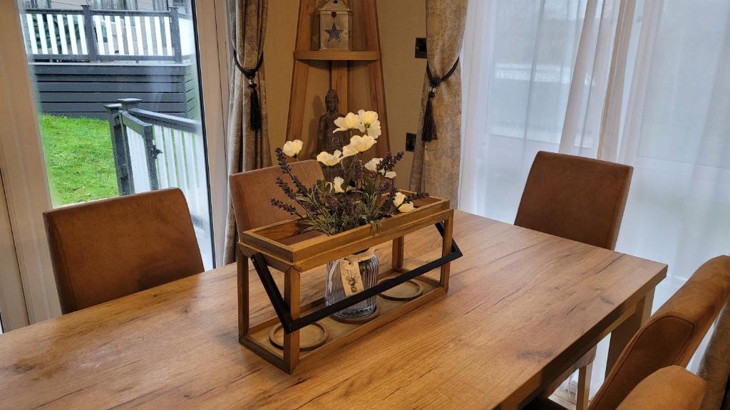 a wooden table with a vase of flowers on it at STUNNING, PEACEFUL LODGE on edge of New Forest and 800m from sea ENTERTAINMENT and LEISURE PASSES INCLUDED in Milford on Sea