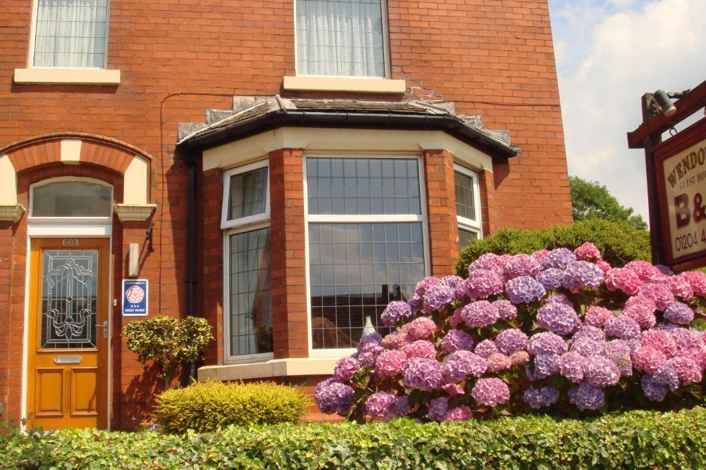 un edificio con un montón de flores púrpuras delante de él en Wendover Guest House, en Bolton