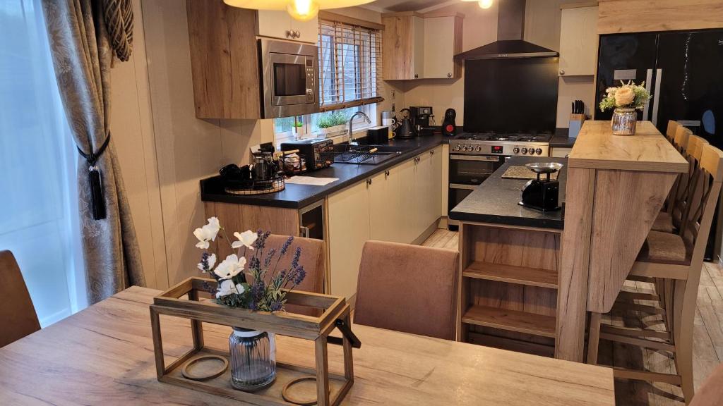 a kitchen with a table and a kitchen with a counter at STUNNING, PEACEFUL LODGE on edge of New Forest and 800m from sea ENTERTAINMENT and LEISURE PASSES INCLUDED in Milford on Sea