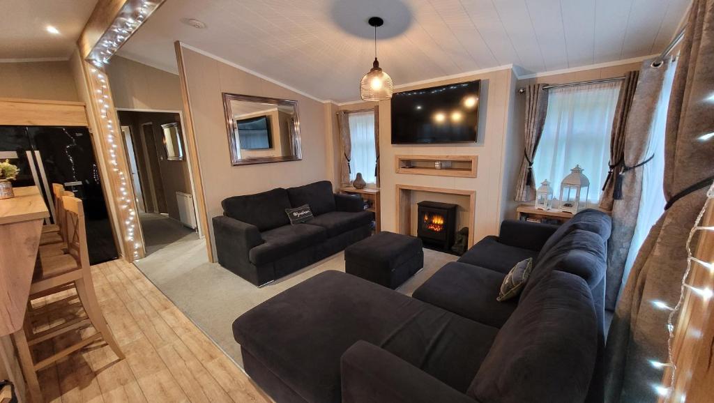a living room with a couch and a fireplace at STUNNING, PEACEFUL LODGE on edge of New Forest and 800m from sea ENTERTAINMENT and LEISURE PASSES INCLUDED in Milford on Sea