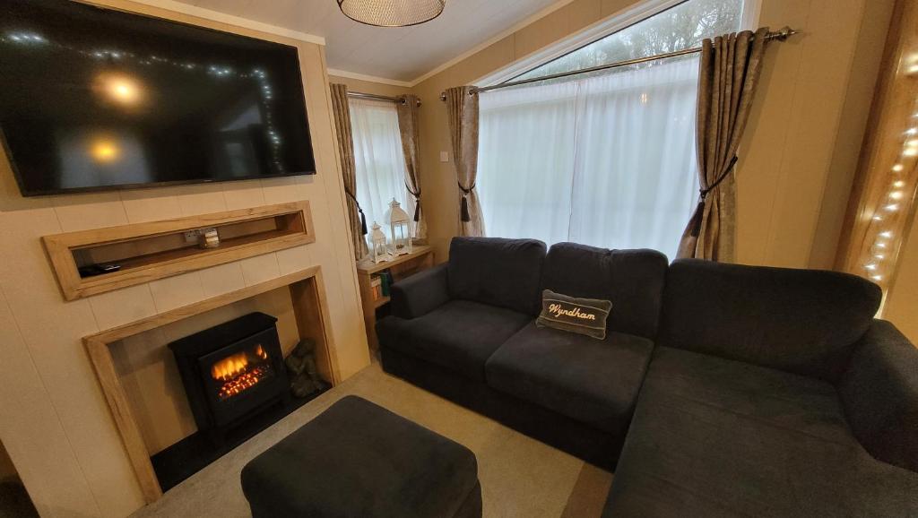 a living room with a couch and a fireplace at STUNNING, PEACEFUL LODGE on edge of New Forest and 800m from sea ENTERTAINMENT and LEISURE PASSES INCLUDED in Milford on Sea