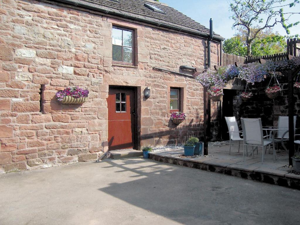 a brick building with a red door and a table and chairs at Elseghyll Barn in Melmerby