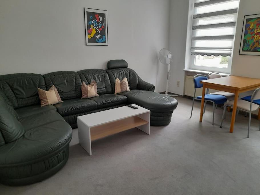 sala de estar con sofá de cuero negro y mesa en Schöne Wohnung für Monteure und sonstige Reisende, en Zwickau