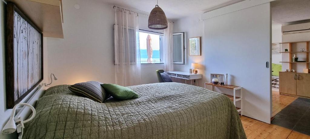 um quarto com uma cama com lençóis verdes e uma janela em Vila Verbana Apartments em Vrbnik