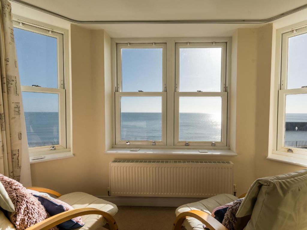 a living room with three windows and the ocean at 13 Great Cliff in Dawlish