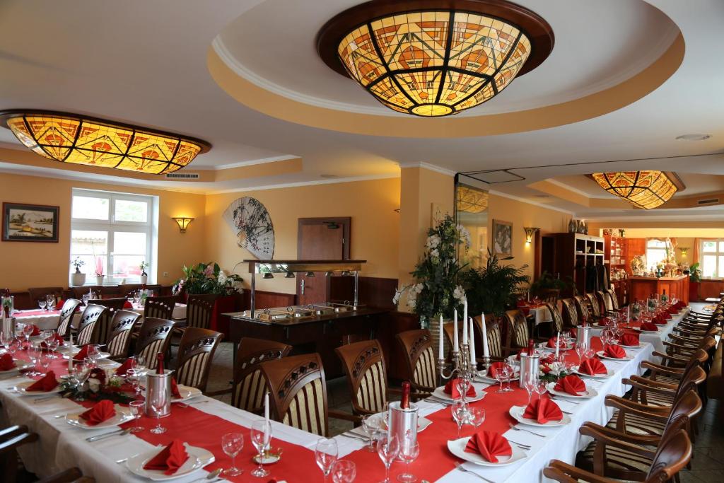 una mesa larga en un restaurante con mesas y sillas rojas en Chau-Asiatisches-Restaurant und Pension en Rüdersdorf