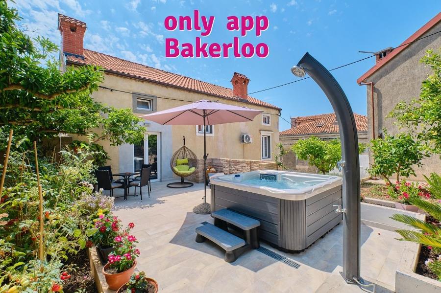un patio trasero con bañera de hidromasaje y sombrilla en SkyGarden House en Mali Lošinj