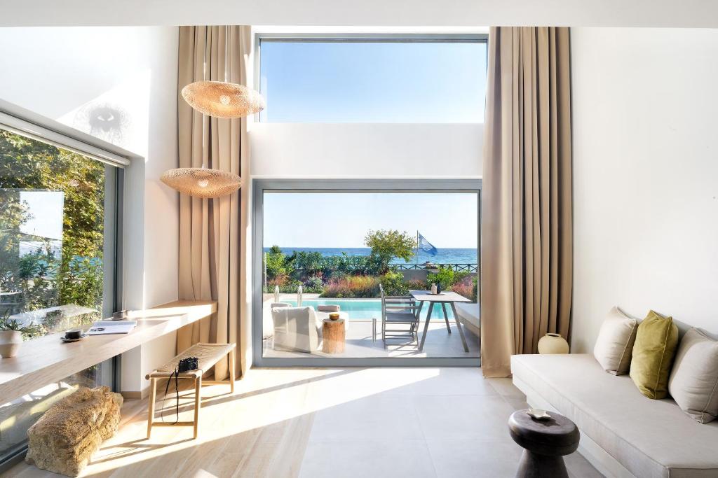 a living room with a couch and a large window at Cavo Delea Villas & Suites in Possidi