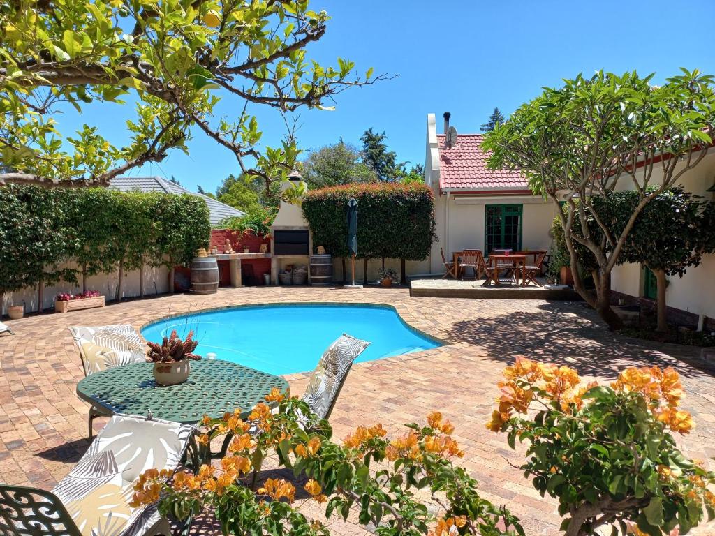 a patio with a table and chairs and a pool at Wine Route 44 Guesthouse in Somerset West