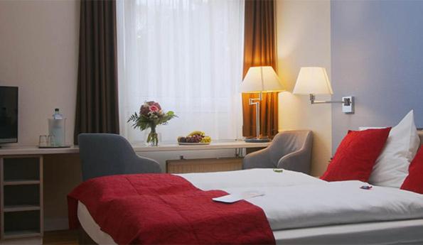 um quarto de hotel com uma cama com um cobertor vermelho em Hotel Novalis Dresden em Dresden