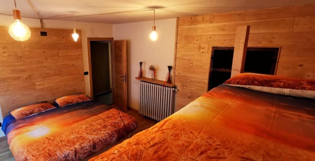 two beds in a room with wooden walls at La Baita D’Nonou in SantʼAnna di Valdieri
