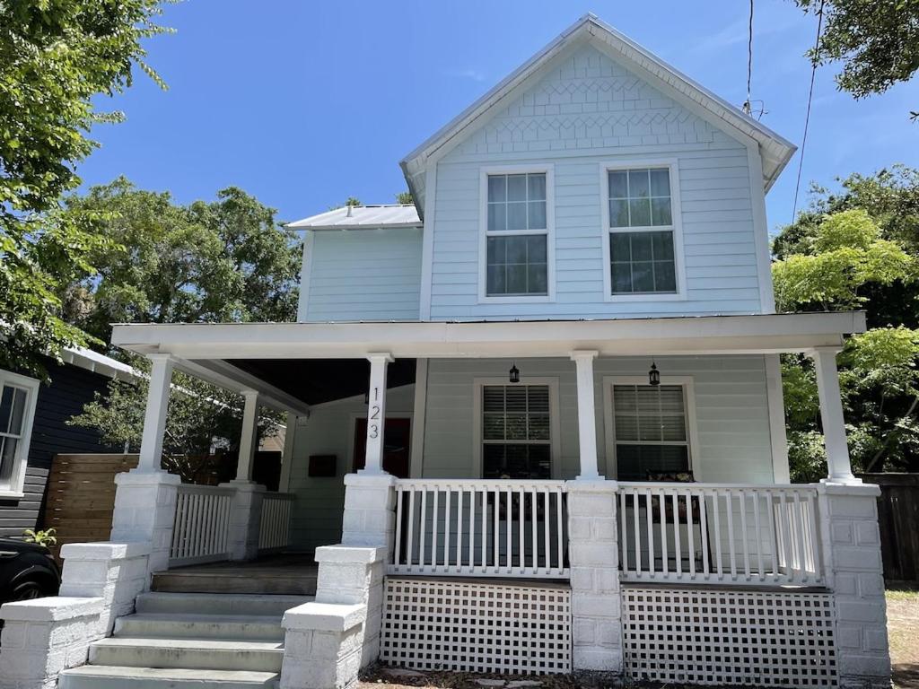 une maison bleue avec une terrasse couverte blanche et des escaliers. dans l'établissement Updated Red Door Revival in Downtown Saint Augustine, à Saint Augustine