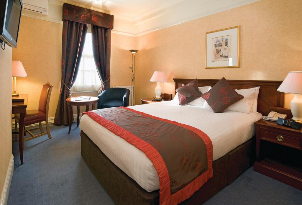 a hotel room with a large bed and a desk at Old Hunstanton Le Strange Arms Hotel in Hunstanton