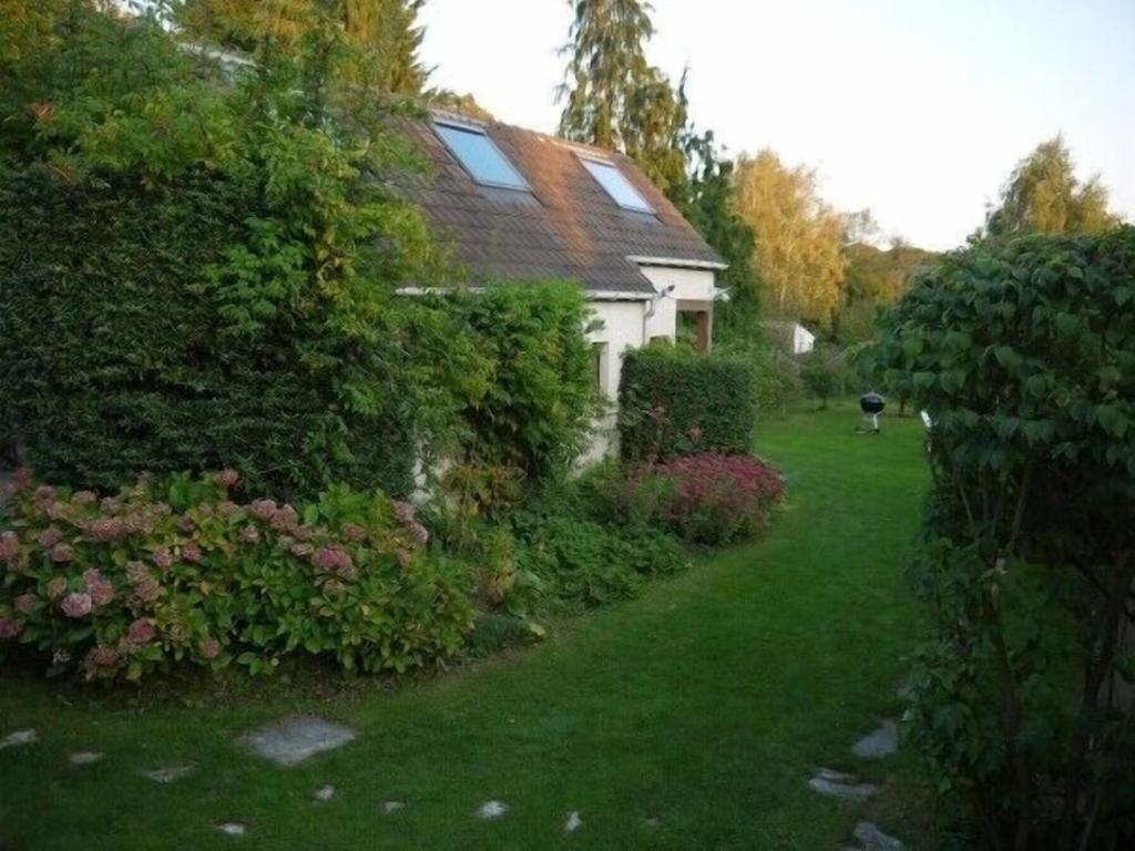 une maison avec une cour verdoyante ornée de buissons et de fleurs dans l'établissement Maisonnette Rambouillet, à Rambouillet