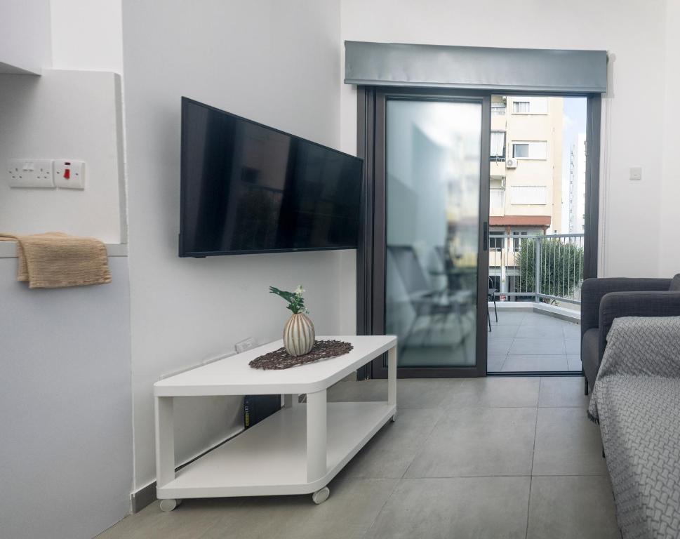 sala de estar con TV y mesa blanca en Lovely 2 Bed Apartment in Larnaca City Centre, en Lárnaca