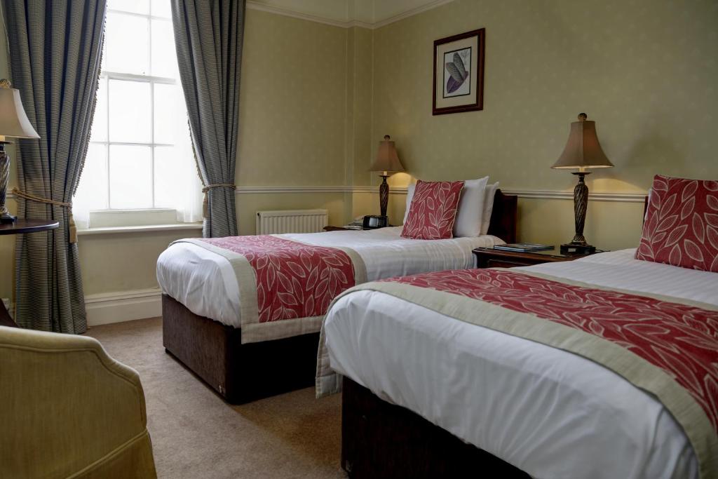 a hotel room with two beds and a window at Old Hunstanton Le Strange Arms Hotel in Hunstanton