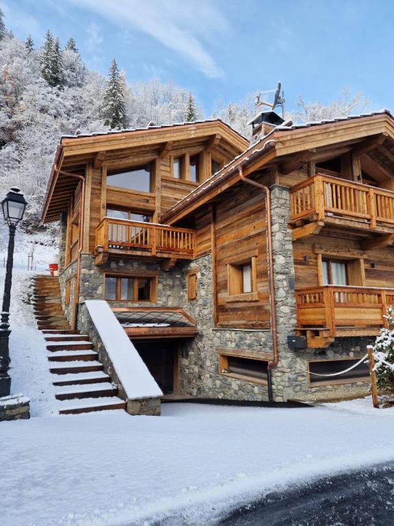 une cabane en rondins en hiver avec de la neige au sol dans l'établissement Chalet Les Cochettes, à Courchevel