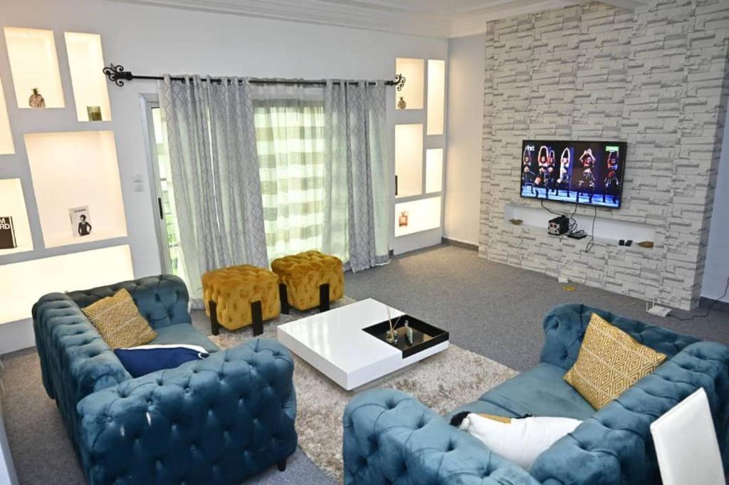 a living room with two blue couches and a tv at Appartement cosy gold bonapriso in Douala