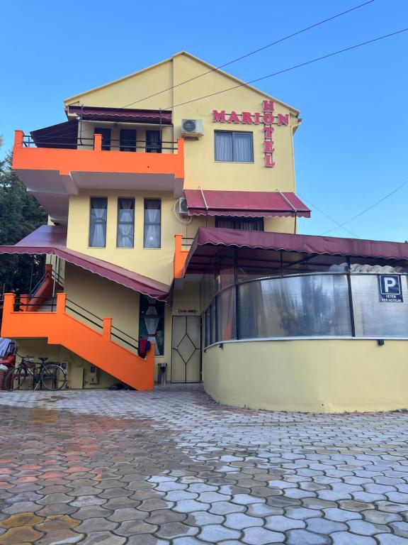 un bâtiment jaune et orange dans une rue pavée dans l'établissement MARION HOTEL, à Tirana